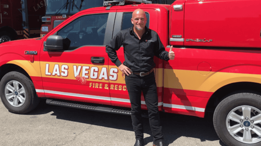 Homme debout donnant un pouce levé devant un véhicule rouge de pompiers Las Vegas