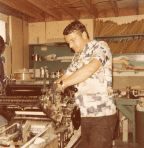 Homme travaillant sur une machine industrielle dans un atelier avec des dossiers en arrière-plan